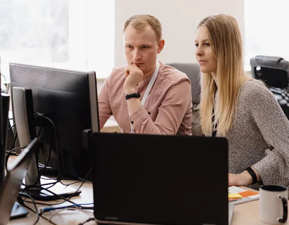 Two colleagues reviewing work at a computer